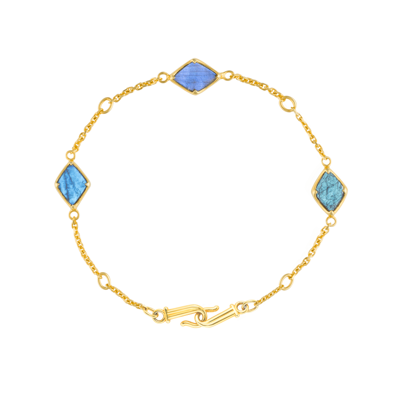 A flat-lay image of the 9ct Gold Blue Labradorite Adjustable Bracelet, Three Wishes, crafted from Fairmined 9ct yellow gold and hand-cut blue labradorites by Juraster.