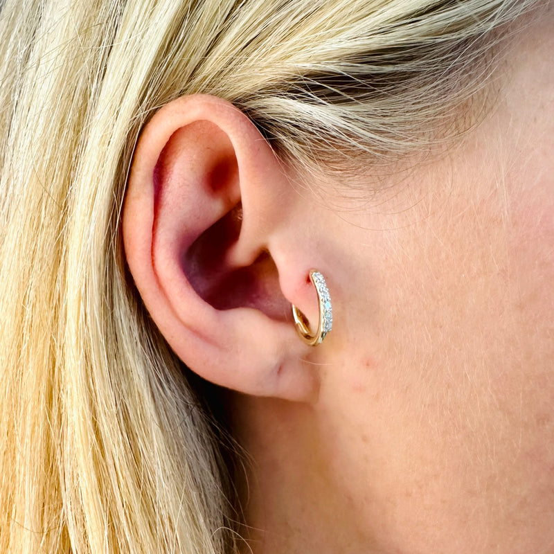 A model wearing Juraster’s 9ct Gold Diamond Hoop Earring, Anchor, crafted from Fairmined yellow gold and conflict-free diamonds, in her tragus.