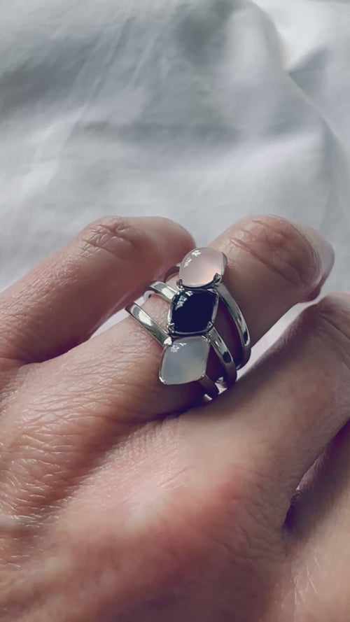 a stack of rings set with rose quartz, black onyx and white chalcedony