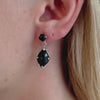 A close-up video of a model wearing Juraster's Sterling Silver Black Onyx Stud Earring, Adventure, crafted from Fairmined sterling silver and hand-cut black onyx, with a matching earring charm attached.