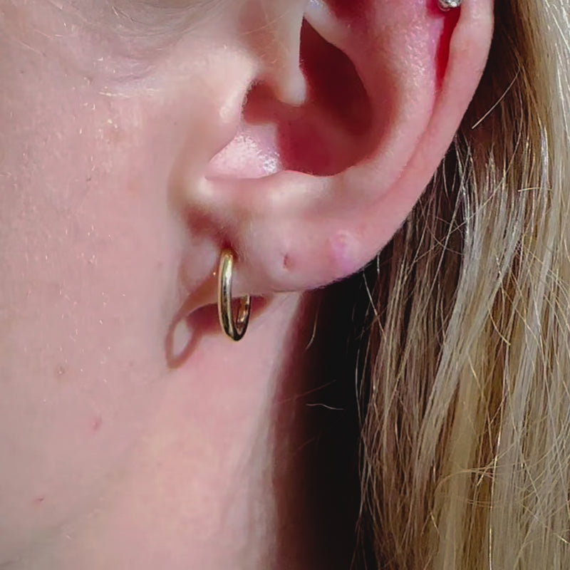 A video of a model wearing Juraster’s 9ct Solid Gold Classic Hoop Earring, Anchor, crafted from Fairmined yellow gold.